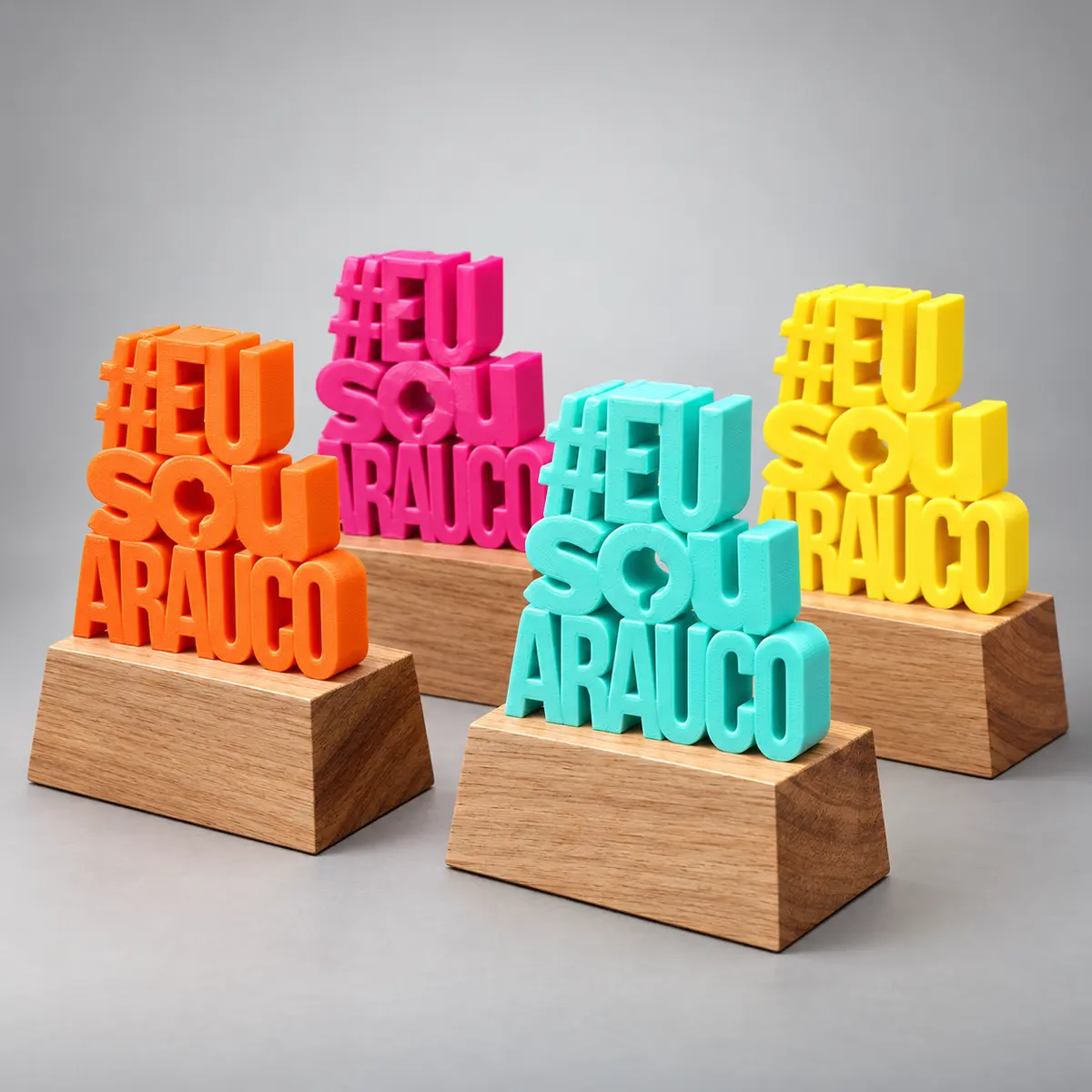 Quatro peças 3D coloridas com a hashtag da empresa, sobre bases de madeira